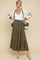 woman wearing a white maternity top and an olive green tiered maxi skirt, styled with a beige and blue cardigan