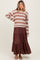 woman wearing a striped brown and beige maternity sweater with a brown tiered maxi skirt and a visible baby bump