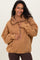 woman wearing a brown maternity pullover hoodie with a half zipper and oversized fit, holding her baby bump