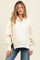 woman wearing a cream maternity pullover sweatshirt with a half-button placket and balloon sleeves, showing her baby bump