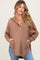 woman wearing a brown maternity hoodie with a button placket and pockets, styled with light blue jeans