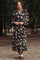 woman wearing a black floral long sleeve maxi dress with a tiered skirt and puff sleeves in a forest setting