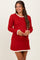 woman wearing a red ribbed maternity dress with white ruffled trim on the neckline and sleeves, smiling and holding her baby bump