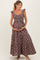 woman wearing a brown floral maternity maxi dress, holding her baby bump with a smile