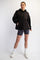woman wearing a black quilted pullover hoodie with buttons, paired with gray bike shorts and white sneakers