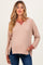 woman wearing a light brown maternity sweater with a v-neck and contrasting sleeves, showing a baby bump