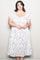 woman wearing a white floral plus-size tea dress with short puff sleeves and a square neckline