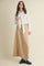 woman wearing a white long sleeve blouse with a tie detail and a beige maxi skirt, styled with black loafers