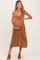 woman wearing a brown maternity dress with a bow detail, holding her baby bump and smiling
