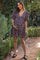 woman wearing a floral maternity dress with puff sleeves and a v-neck, holding her baby bump in a garden setting