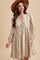 woman wearing a cream floral print long sleeve dress with a v-neck and pom pom hem, accessorized with a wide-brimmed hat