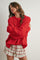 woman wearing a bright red oversized knitted sweater and a floral ruffled mini skirt