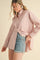 woman wearing a light pink striped long sleeve shirt with a pocket and denim shorts