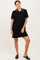 woman wearing a black short sleeve polo dress with contrasting collar and cuffs, posing confidently