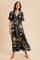 woman wearing a black floral maxi dress with short sleeves and a button-down front, styled with beige flats