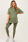 woman wearing an olive green maternity t-shirt and matching leggings, holding her baby bump
