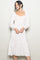 woman wearing a white midi dress with red polka dots and long puff sleeves, smiling against a light background