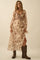 woman wearing a cream and brown floral maxi dress with long sleeves and a deep v-neck, paired with brown knee-high boots
