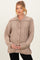 woman wearing a beige cable knit maternity cardigan and holding her baby bump