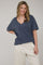 woman wearing a navy blue oversized v-neck t-shirt with loose cream sweatpants and smiling