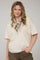 woman wearing a beige oversized t-shirt with a decorative scarf around her neck and styled hair