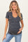 woman wearing a navy and cream striped maternity top with short sleeves and a scoop neckline, holding her baby bump