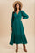 woman wearing a green long sleeve button-up dress with a tiered skirt and a wide-brimmed hat, paired with brown boots