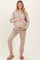 woman wearing a beige maternity sweatshirt and matching joggers, holding her baby bump