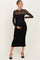 woman wearing a black maternity dress with a sheer long sleeve overlay and ruched details, showcasing her baby bump