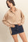 woman wearing a beige long sleeve satin button-up shirt paired with a dark denim mini skirt