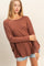 woman wearing a rust long sleeve oversized top paired with denim shorts