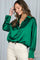 woman wearing a green satin oversized button-up shirt and cream-colored jeans