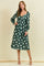 woman wearing a green floral midi dress with long sleeves and a v-neckline, standing against a light background