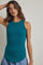 woman wearing a teal ribbed sleeveless top with a high neck and slightly curved hem