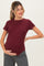 woman wearing a maroon short sleeve maternity top with a rounded hem and holding her baby bump