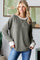 woman wearing a green ribbed long sleeve top with contrasting white cuffs and a relaxed fit, smiling casually