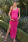 woman wearing a bright pink maternity maxi dress with a side slit and holding her baby bump