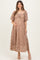 woman wearing a blush lace maternity dress with puff sleeves and a tie detail, holding her baby bump