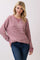 woman wearing a mauve striped long sleeve oversized sweatshirt with a v-neck and relaxed fit, paired with blue jeans