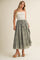 woman wearing a white smocked crop top and a long olive green tiered maxi skirt with tassel detail