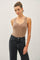 woman wearing a beige ribbed tank top and high-waisted black jeans