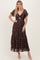 woman wearing a dark floral maxi dress with short flutter sleeves and a front cutout detail
