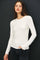 woman wearing a white long sleeve fitted top with a round neckline and black jeans