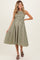 woman wearing a green and white gingham maternity dress with a fitted bodice and flowy skirt, showcasing her baby bump