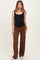 woman wearing a black maternity tank top and brown flowy maternity pants, showing her baby bump