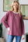woman wearing a raspberry-colored long sleeve waffle knit pullover with cream cuffs and a relaxed fit