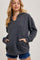 woman wearing a dark gray hooded sweatshirt with a front pocket and a relaxed fit paired with denim shorts