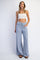 woman wearing a white cropped tank top and light blue wide-leg pants with pockets and drawstring waist