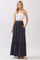woman wearing a white strapless top and a navy blue maxi skirt with button details and pockets
