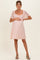 woman wearing a pink lace maternity dress with short puff sleeves and a visible baby bump